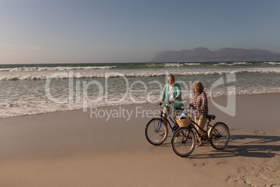 Senior couple walking with bicycle on the beach