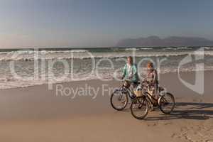 Senior couple walking with bicycle on the beach