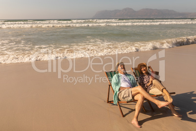 Senior couple having fun while relaxing on sun lounger at beach