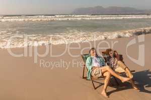 Senior couple having fun while relaxing on sun lounger at beach