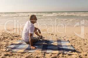 Senior man relaxing on picnic blanket at beach