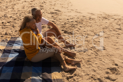 Senior couple relaxing on picnic blanket at beach