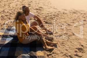 Senior couple relaxing on picnic blanket at beach