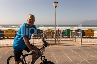 Senior man riding a bicycle on a promenade at beach