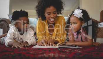 African American mother with her cute children lying on floor and reading a storybook