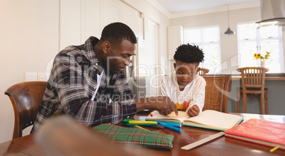 African American father helping his son with homework at table