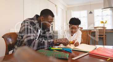 African American father helping his son with homework at table