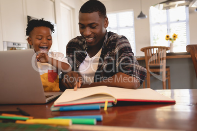 African American father helping his son with homework at table