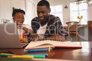 African American father helping his son with homework at table