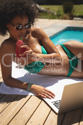 Young African American woman using laptop in her backyard
