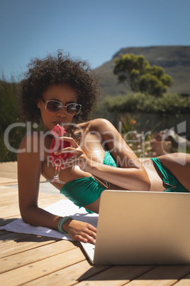 Young African American woman using laptop in her backyard