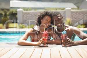 Happy young African American couple leaning on edge of pool and looking at camera