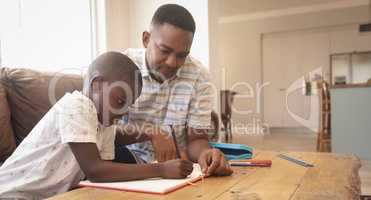 African American father helping his son with homework at table
