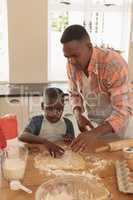 African American father and son baking cookies in kitchen