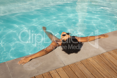 Young mixed-race woman relaxing with sunglasses in pool