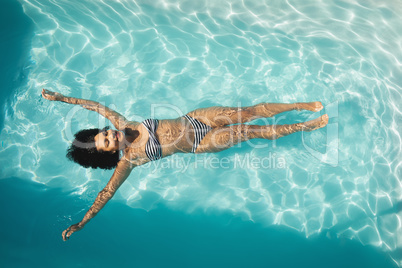 Young mixed-race woman floating in swimming pool