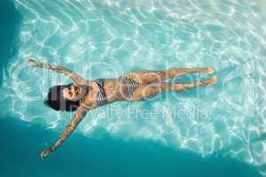 Young mixed-race woman floating in swimming pool