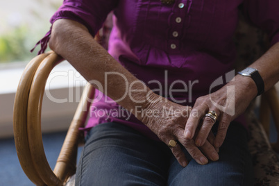 Senior woman with folded hands on her lap at home