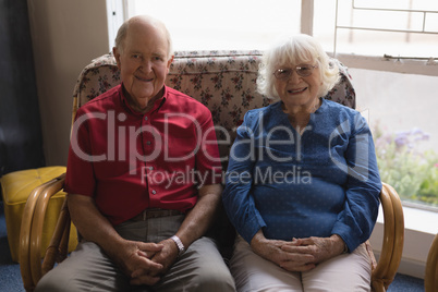 Front view of senior couple with hand clasped looking at camera in nursing home