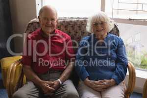 Front view of senior couple with hand clasped looking at camera in nursing home