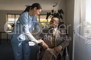 Front view of female doctor talking with senior man at nursing home