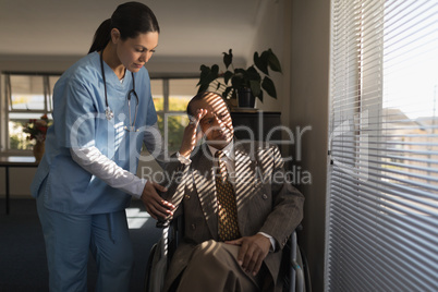 Female doctor consoling sad disable senior man at nursing home