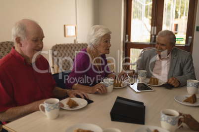 Front view of happy group of senior friends having breakfast on dining table