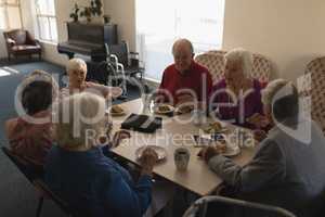 High angle view of group of senior friends having breakfast on dining table