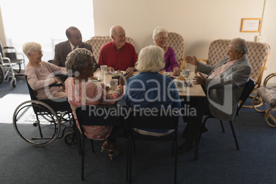 Group of senior friends having breakfast on dining table at nursing home