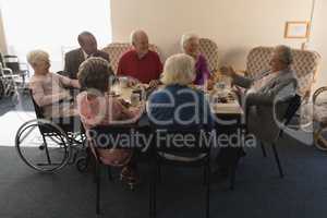 Group of senior friends having breakfast on dining table at nursing home