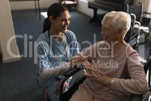 Front view of female doctor talking with disable senior woman at nursing home