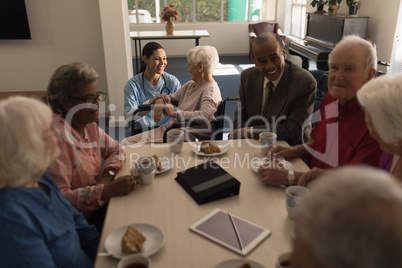 Group of senior friends having breakfast on dining table at nursing home