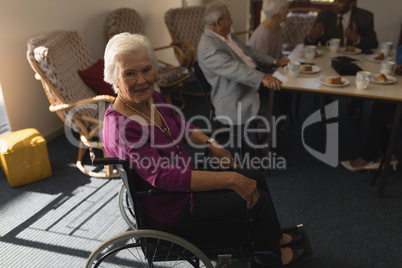Side view of disable senior woman sitting on wheel chair and looking at camera