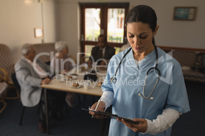 Front view of female doctor looking at clipboard at nursing home