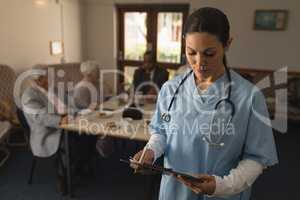 Front view of female doctor looking at clipboard at nursing home