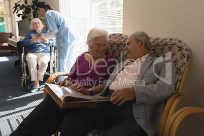 Front view of senior couple looking photo album on sofa