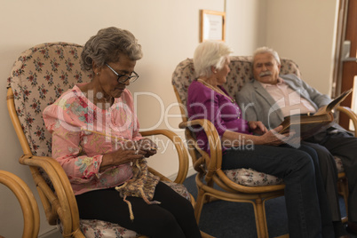 Senior friends knitting and looking photo album at nursing home