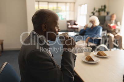 Side view of senior man drinking coffee on dining table