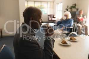 Side view of senior man drinking coffee on dining table