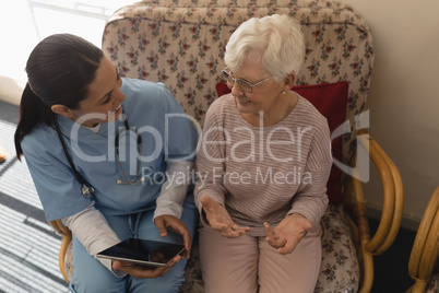 High angle view of female doctor discussing medical report with senior woman on digital tablet