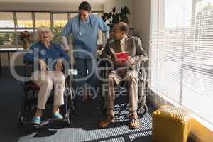 Front view of female doctor talking with disable senior couple at home