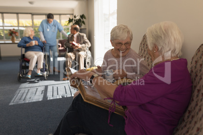 Side view of senior women looking photo album on sofa at home