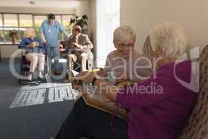 Side view of senior women looking photo album on sofa at home