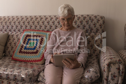 Front view of senior woman using digital tablet on sofa