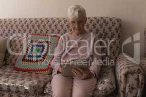 Front view of senior woman using digital tablet on sofa