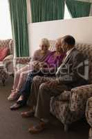 Front view of senior friends discussing over digital tablet while sitting on sofa