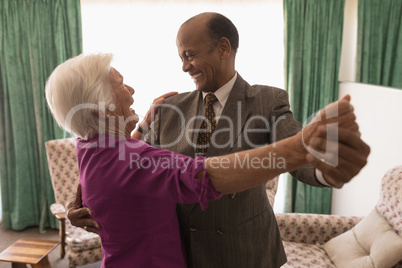 Happy senior couple dancing together at home