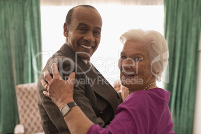 Side view of happy senior couple looking at camera while dancing