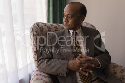 Front view of senior man with hand clasped looking away at home