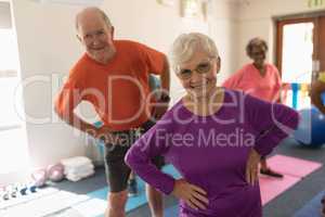 Front view of senior couple exercising in fitness studio